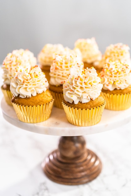 Cupcake aux épices à la citrouille avec crème au beurre italienne et pépites sur un présentoir à gâteaux.