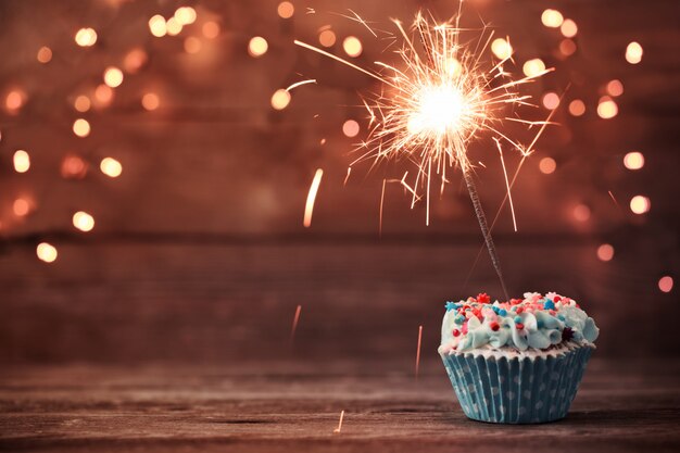 Cupcake avec cierge magique sur fond en bois ancien