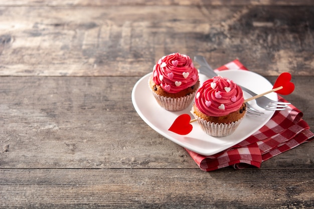 Cupcake décoré de coeurs de sucre et d'une flèche de Cupidon pour la Saint Valentin sur table en bois