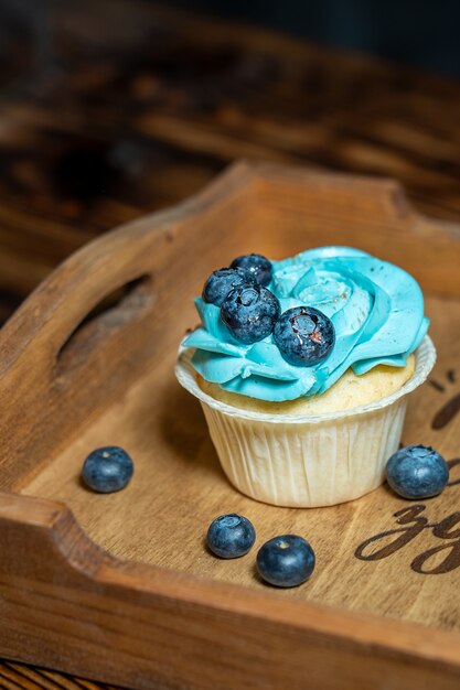 Cupcake fait maison sucré unique décoré de garniture de fromage à la crème bleu et de myrtilles sur plateau