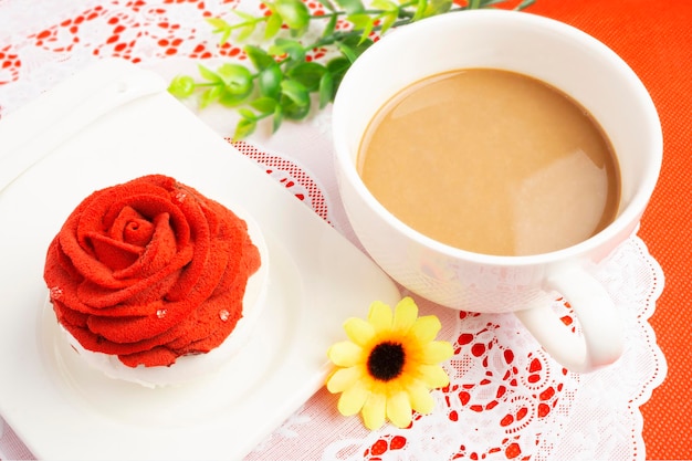 Photo cupcake festif surmonté d'une décoration rose rouge servi avec du café chaud