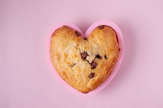 Cupcake en forme de coeur avec des morceaux de chocolat sur fond rose gros plan