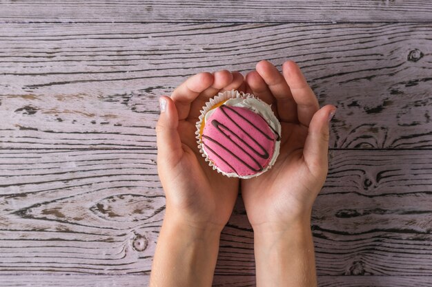 Cupcake frais entre les mains d'un enfant sur une table en bois