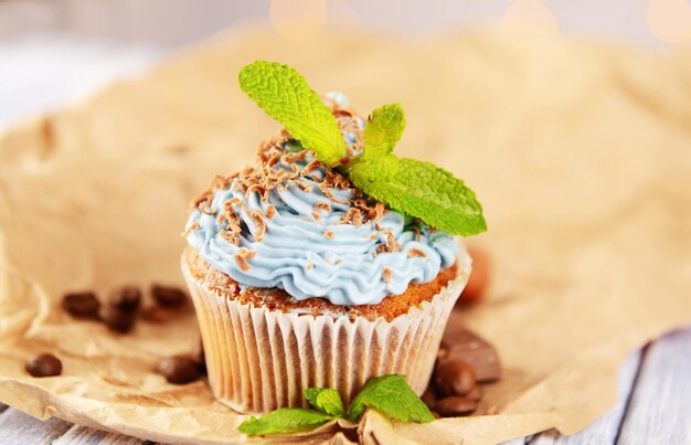 Cupcake savoureux avec de la crème au beurre sur une table en bois de couleur sur fond de lumières