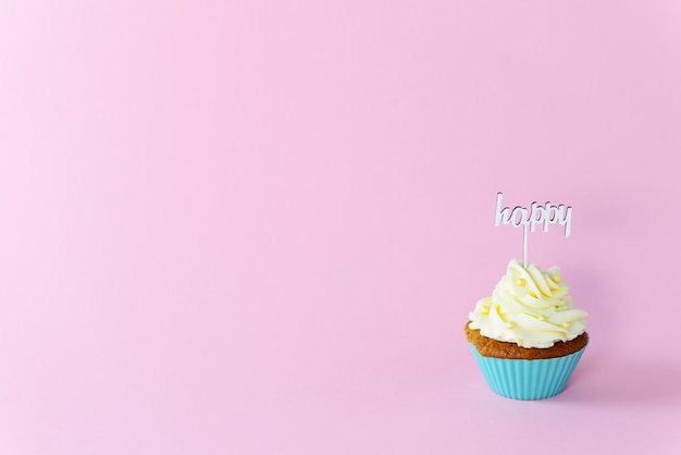 Photo cupcake avec topper heureux sur fond rose