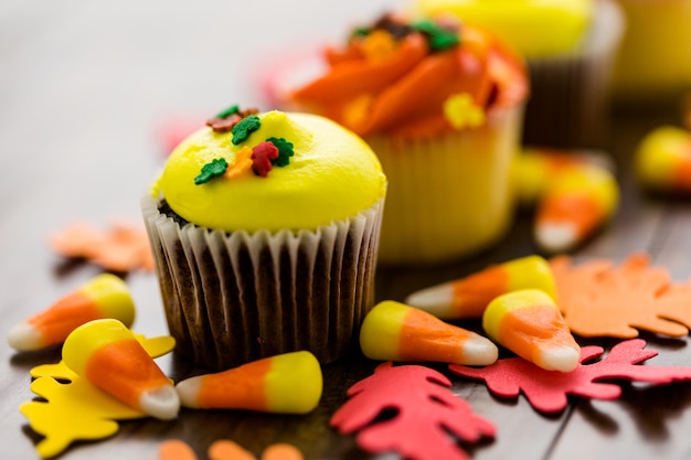 Cupcakes assortis avec glaçage jaune et orange décorés pour l'automne.