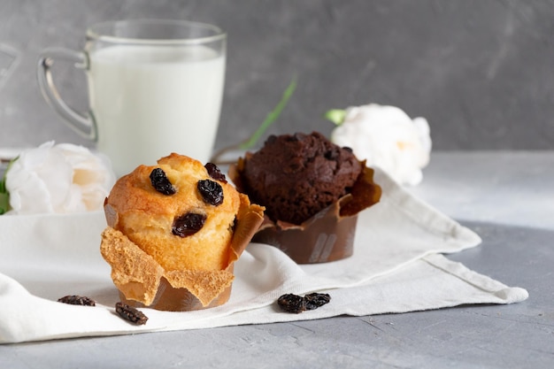 Photo cupcakes au chocolat aux raisins secs et verre de lait et fleurs sur fond