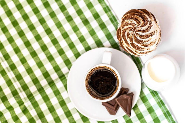 Cupcakes au chocolat noir et au chocolat cacao avec une tasse de café noir chaud sur une serviette verte Espace pour le texte