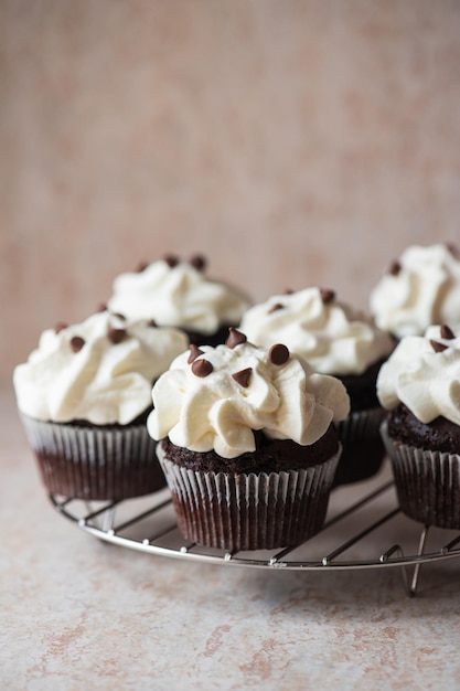 Cupcakes au chocolat riche avec glaçage à la crème fouettée et pépites de chocolat sur une grille de refroidissement Gros plan