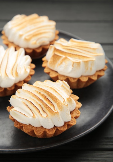 Cupcakes au citron appétissants avec de la crème blanche sur une assiette sombre. Vacances, surprise, anniversaire, Saint Valentin. Photographie verticale.