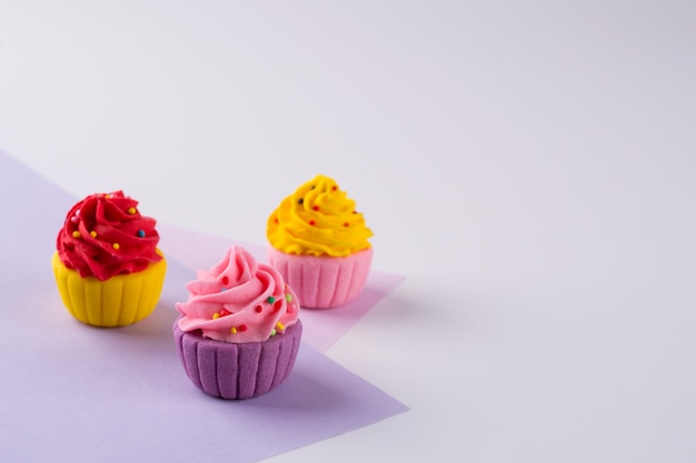 Cupcakes au sucre multicolores décoratifs sur fond clair avec des paillettes