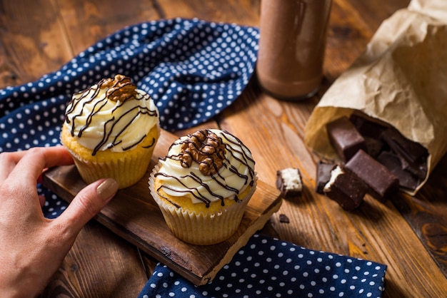 Cupcakes et une bouteille avec une boisson au lait sur une table en bois