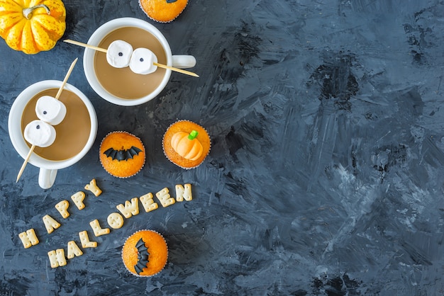 Photo cupcakes à la citrouille d'halloween avec des tasses de café et des yeux de guimauve, espace copie