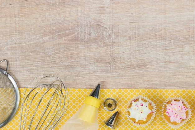 Cupcakes colorés et outils de cuisson sur une table en bois.