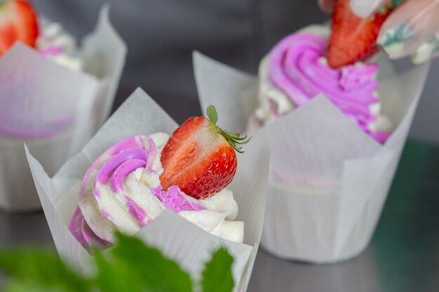 cupcakes avec crème au beurre rose et baies fraîches dans des étuis en papier sulfurisé blanc sur une table en métal