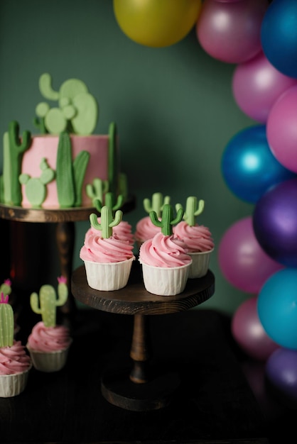 Cupcakes à la crème rose décorés de cactus. Table d'anniversaire douce d'été.