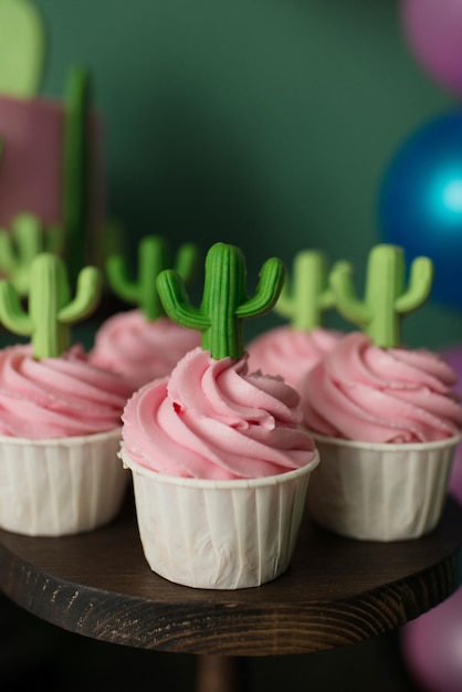 Cupcakes à la crème rose décorés de cactus. Table d'anniversaire douce d'été.