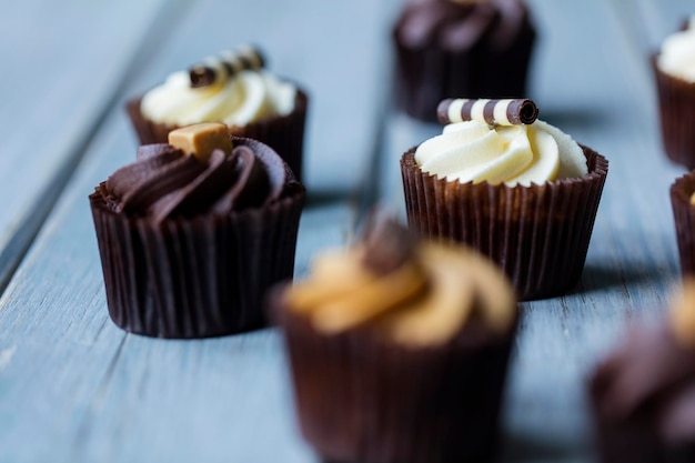 Cupcakes décorés de glaçage chocolat-caramel et vanille sur fond de bois