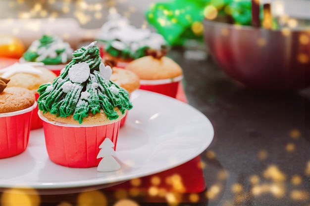 Cupcakes en forme d'arbre de Noël avec des pépites de neige sur les lumières de Noël et fond festif Cuisiner un traitement de Noël pour la famille