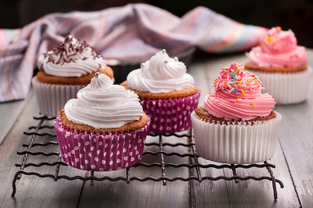 Cupcakes sur une grille de refroidissement avec glaçage rose et blanc sur le dessus.