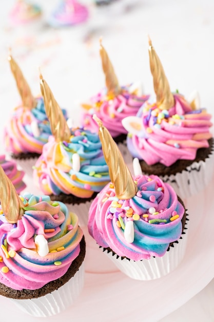 Photo cupcakes licorne décorés de glaçage au beurre coloré et de pépites.