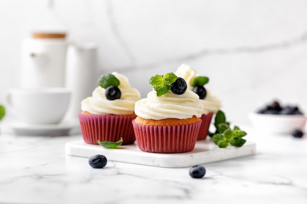 Photo cupcakes muffins décorés de baies à la crème et de feuilles de menthe verte délicieux dessert maison