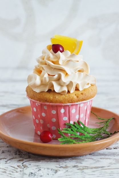 Photo cupcakes de noël avec garniture à la crème fouettée et canneberges, orange. dessert de nourriture festive.