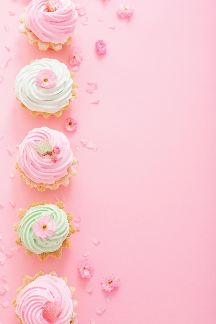 Photo cupcakes roses et verts avec des fleurs de printemps sur fond rose