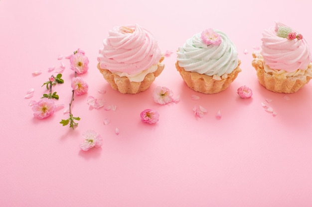 Cupcakes roses et verts avec des fleurs de printemps sur fond rose