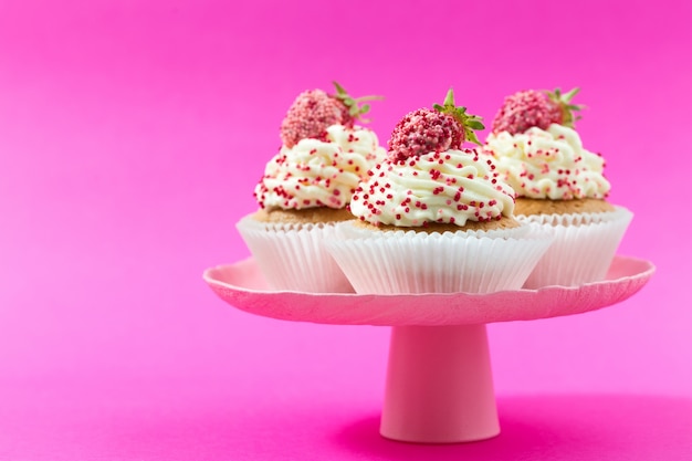 Photo cupcakes vanille aux fraises sur fond rose