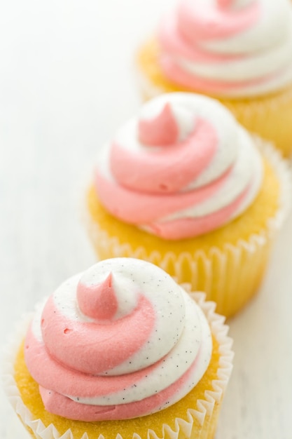Cupcakes à la vanille garnis de crème à la fraise.