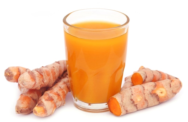 Curcuma frais avec extrait dans un verre sur fond blanc