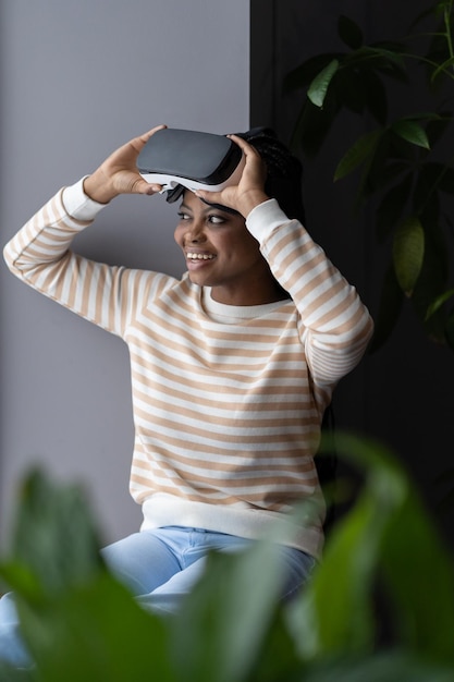 Photo curieuse femme noire joyeuse se sentant excitée par le casque vr tout en passant du temps libre à la maison