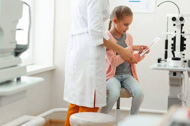 Curieuse petite fille assise dans une armoire ophtalmologiste équipée