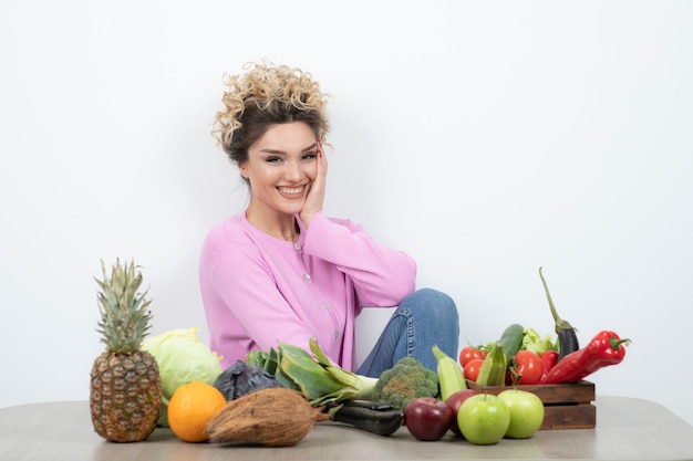 Curly femme assise à table avec beaucoup de légumes frais.