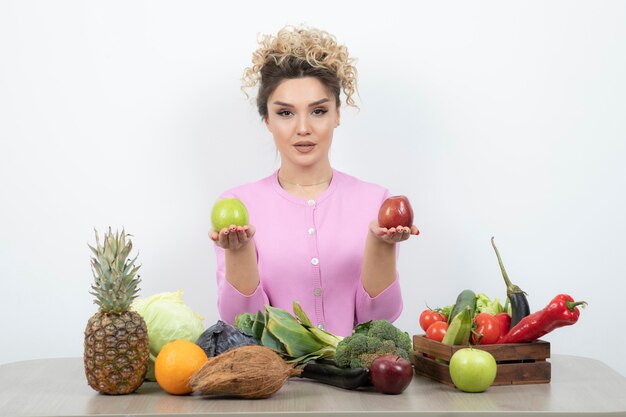 Curly femme assise à table tenant de délicieux fruits.