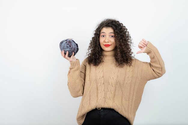 Curly jeune femme tenant le chou violet donnant les pouces vers le bas.