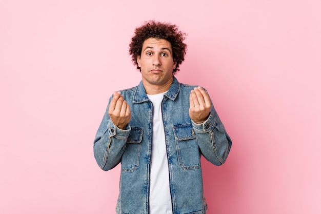 Curly mature man wearing a denim jacket montrant qu'il est fauché