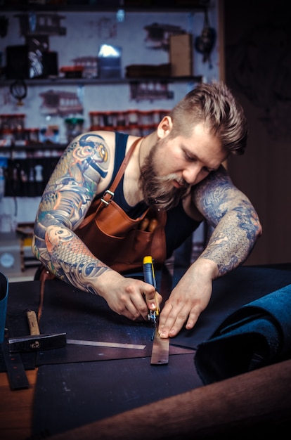 Currier de cuir travaillant sur un nouveau produit en cuir dans l'atelier de tannerie