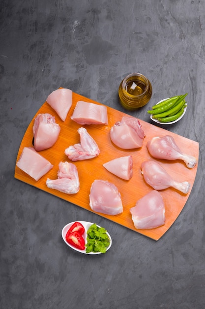 Photo curry tendre de poulet cru coupé avec peau disposée sur planche de bois