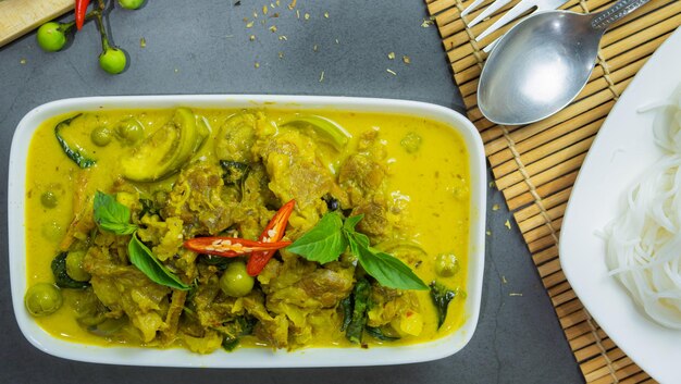 Photo curry vert avec du bœuf c'est un aliment célèbre en thaïlande. la nourriture se compose d'une pâte de curry mélangée à des herbes, cuite à feu vert avec du lait de coco et de la viande. saisonnée avec de la sauce au poisson et du sucre.