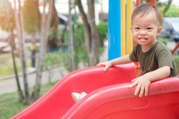 Photo cute smiling little asian1 ans bébé garçon enfant jouant sur un toboggan dans l'aire de jeux