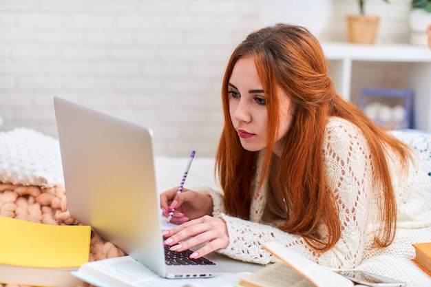 Cute Teen Femme Fait Ses Devoirs En Position Couchée Sur Le Lit à La Maison