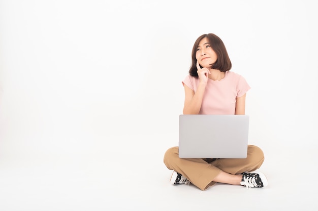 Cute teen teen asiatique travaille avec ordinateur sur mur blanc