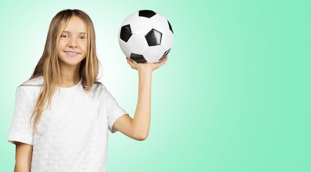 Cutie petite fille en chemise blanche tenant un ballon de football dans les mains