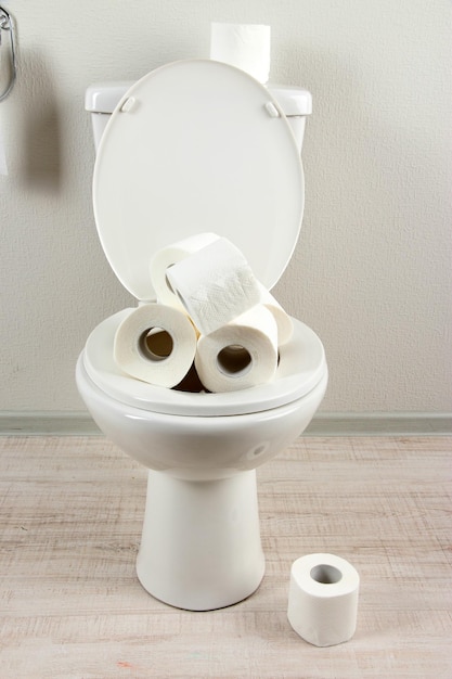 Cuvette de toilette blanche avec papier toilette dans une salle de bain