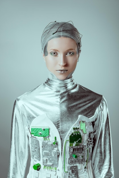 Cyborg féminin argenté futuriste regardant la caméra isolé sur le concept de technologie du futur gris