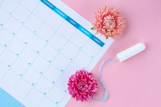 Cycle menstruel régulier. Tampons, calendrier féminin, fleurs. Soins d'hygiène pendant les jours critiques. Soins de santé pour femmes et gynécologiques.