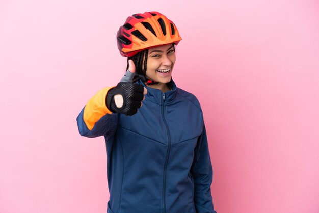 Cycliste adolescente isolée sur fond rose avec les pouces vers le haut parce que quelque chose de bien s'est produit