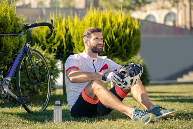 Cycliste assis sur l'herbe près du vélo